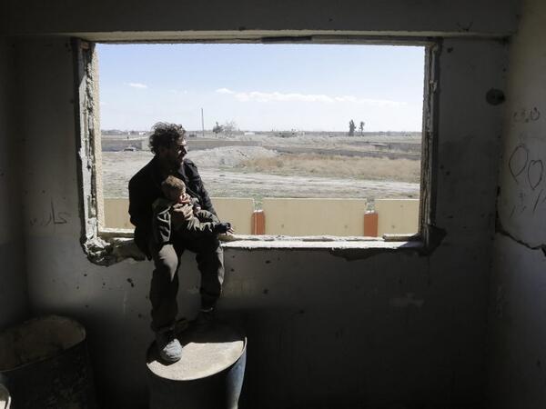 A Syrian man carries a child, after being evacuated from rebel-held areas in the Eastern Ghouta, at a school in the regime-controlled Hosh Nasri, on the northeastern outskirts of the capital Damascus on Mar.16, 2018, ahead of being relocated to other areas. (LOUAI BESHARA / AFP)