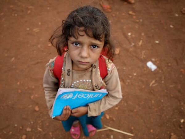 A Syrian child who fled with her family from the northern countryside of Hama, holds a book in the yard of the makeshift school of "Zuhur al-Mustaqbal" (in Arabic "Flowers of the Future") in al-Jeneinah camp for displaced people in the village of Atme, in Syria's mostly rebel-held northern Idlib province, on October 1, 2018. Aaref WATAD / AFP