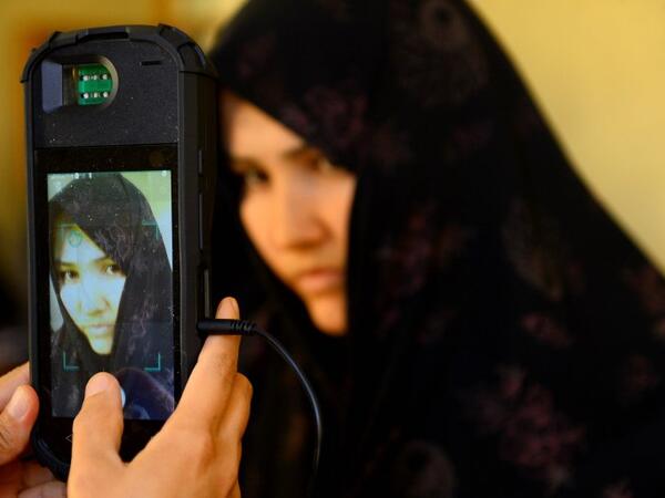 An Afghan Independent Election Commission (IEC) official scans a voter's face with a biometric device at a polling centre for the country's legislative election in Herat province on October 20, 2018. 
HOSHANG HASHIMI / AFP