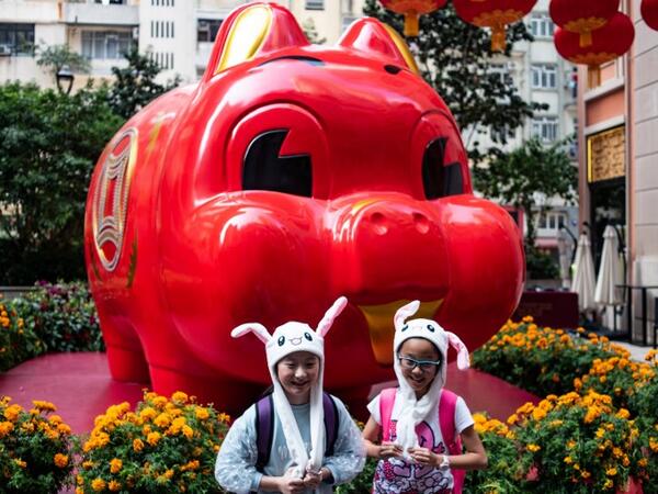 Children in animal hats pose in front of a giant pig installation ahead of the Lunar New Year in Hong Kong on February 4, 2019. 
Philip FONG / AFP