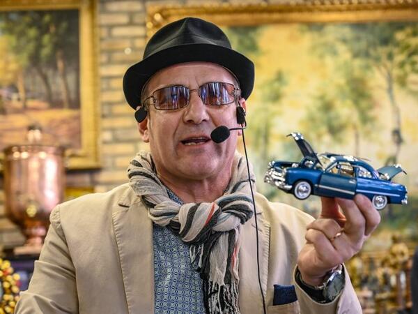 Auctioneer Ali Tuna shows items to the audience at an auction house in Istanbul's Balat district. 
OZAN KOSE / AFP