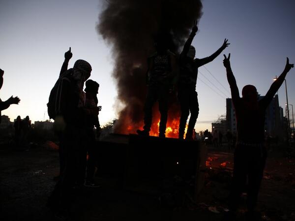 Palestinian demonstrators gesture as they stand on a trash container during clashes with Israeli forces near an Israeli checkpoint in the West Bank city of Ramallah.
(ABBAS MOMANI / AFP)