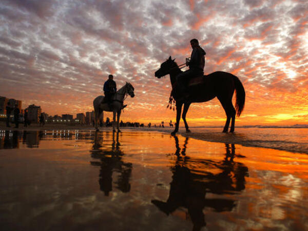 Men riding horses on the beach as the sun sets over Gaza City on January 20, 2017. (AFP PHOTO / MOHAMMED ABED)


