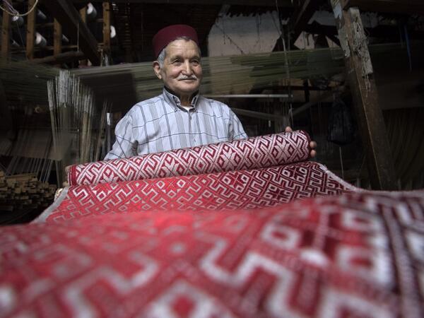 Abdelkader Ouazzani, the last of Morocco's brocade master weavers, displays tapestry at his workshop in the old city of Fez on April 10, 2019. His skilfull hands intricately create shimmering silk fabrics, enhanced with gold or silver thread, for bridal jewellery, designer creations or high-end furnishings. FADEL SENNA / AFP