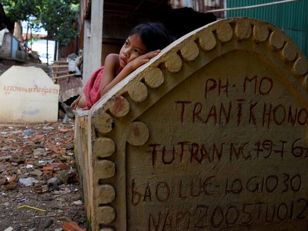 This picture shows a girl lying on a grave in Phnom Penh.  TANG CHHIN Sothy / AFP