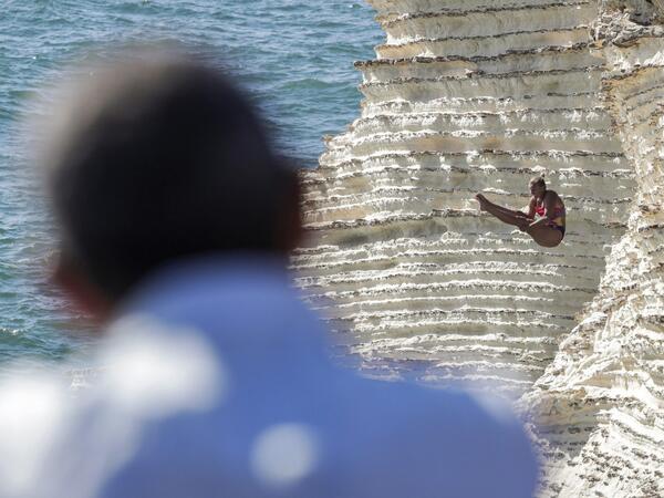 A cliff diver jumps from a platform on the landmark Raouche sea rock off the coast of the Lebanese capital Beirut on July 14, 2019, during the women's 2019 Red Bull Cliff Diving World Series.  ANWAR AMRO / AA / AFP