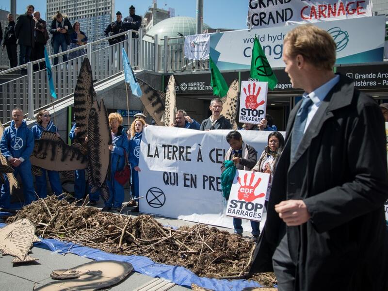 A man walks past activists of 'Extinction Rebellion' (XR) and NGO 'Planete Amazone' as they stage a protest against large hydroelectric dams in front of the Grande Arche de La Defense, in Puteaux, northwest of Paris, on May 14, 2019. AFP