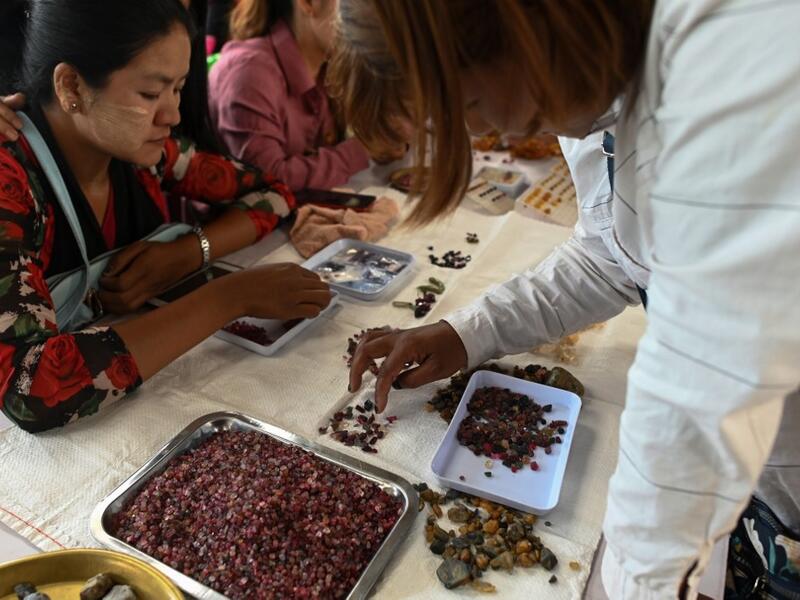 This photo taken on May 17, 2019 shows a buyer inspecting rubies at the gems market in Mogok town, north of Mandalay. Burrowing deep underground, thousands of informal miners risk their lives to find gleaming red gems as a law change spurs opportunity in Myanmar's "land of rubies". Ye Aung THU / AFP