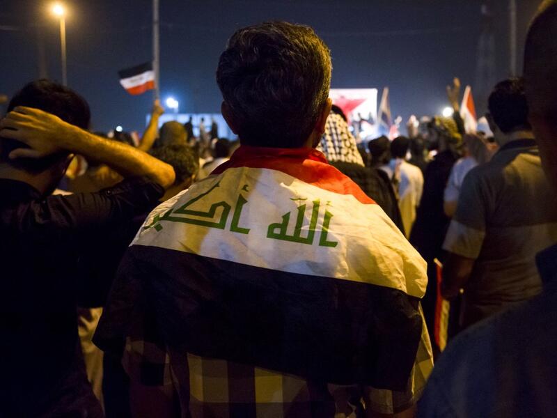 An Iraqi follower of Shiite Muslim cleric Moqtada al-Sadr stands wearing a national flag around his shoulders while demonstrating in the southern city of Basra on May 24, 2019, against involvement in any conflict between Iran and the United States.  Hussein FALEH / AFP