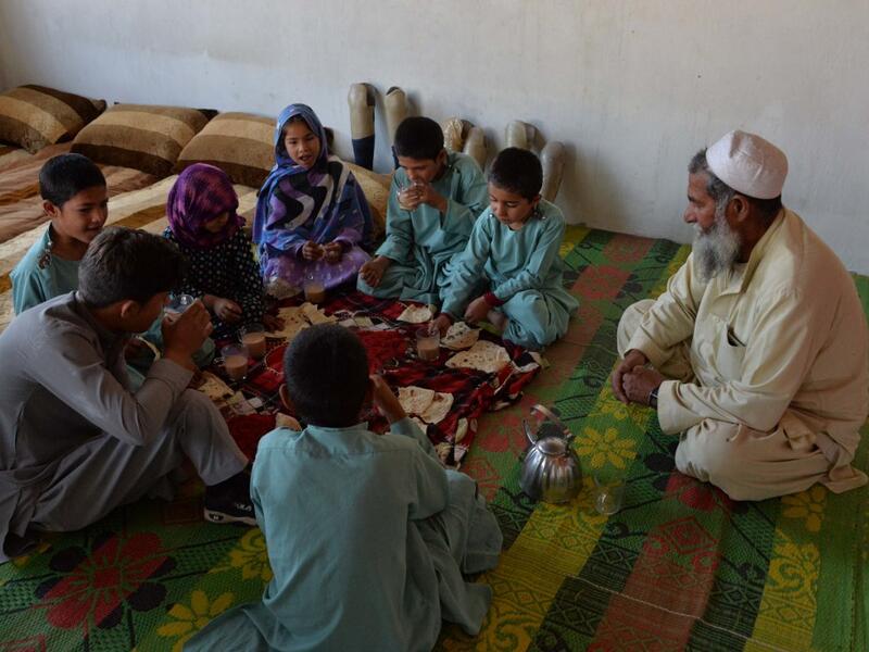 In this photograph taken on May 3, 2019, Afghan man Hamisha Gul 65, looks as his disabled children eat breakfast in their house in the Khogyani district of Nangarhar province. NOORULLAH SHIRZADA / AFP