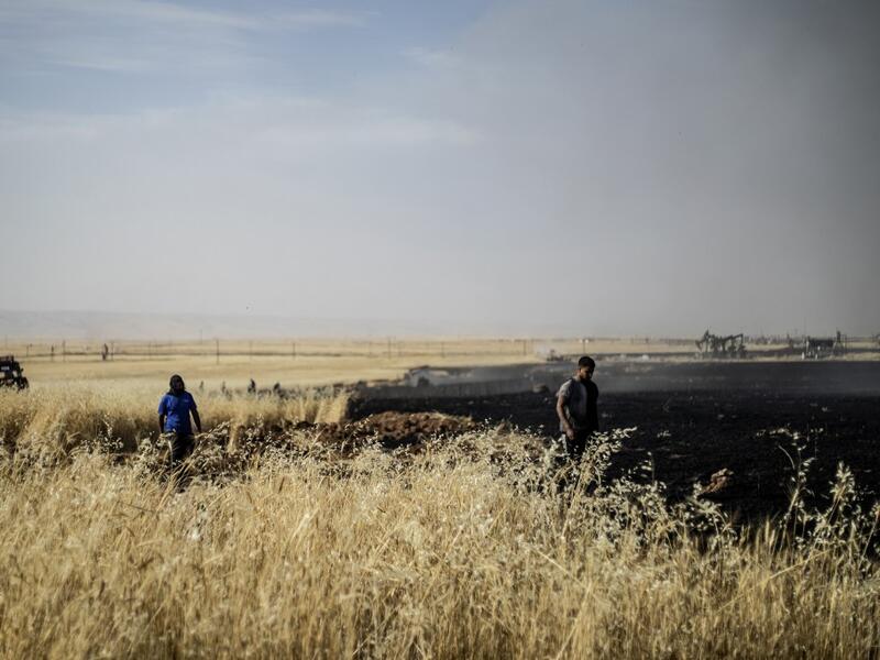 People battle a blaze next to an oil well in an agricultural field in the town of al-Qahtaniyah, in the Hasakeh province near the Syrian-Turkish border on June 10, 2019. Fires have erupted in various parts of Syria in recent weeks, with all sides blaming each other for starting them. Delil souleiman / AFP