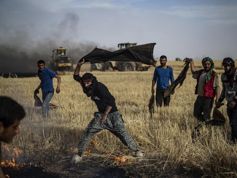 People battle a blaze next to an oil well in an agricultural field in the town of al-Qahtaniyah, in the Hasakeh province near the Syrian-Turkish border on June 10, 2019. Fires have erupted in various parts of Syria in recent weeks, with all sides blaming each other for starting them. Delil souleiman / AFP