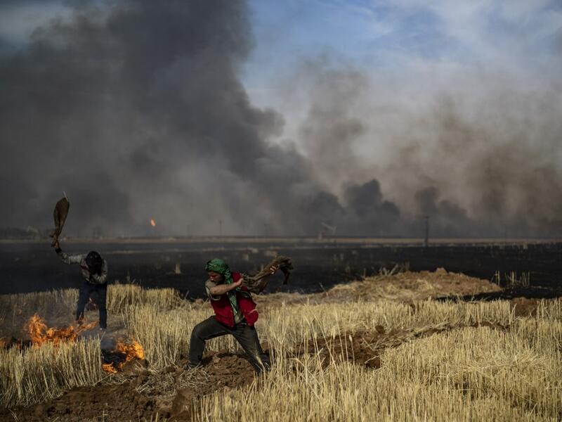 People battle a blaze in an agricultural field in the town of al-Qahtaniyah, in the Hasakeh province near the Syrian-Turkish border on June 10, 2019. Fires have erupted in various parts of Syria in recent weeks, with all sides blaming each other for starting them. Delil souleiman / AFP