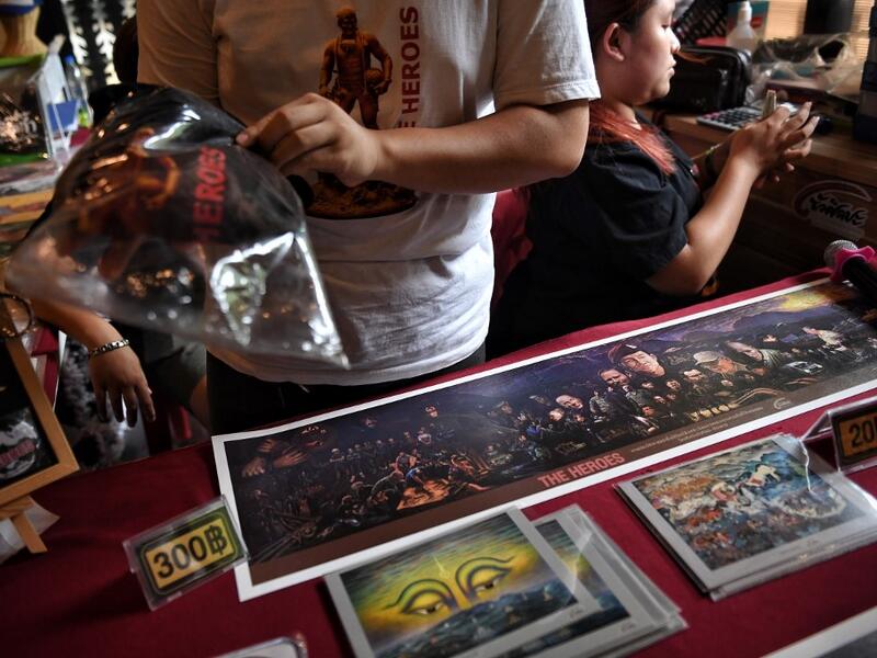 This picture taken on June 13, 2019 shows vendors selling memorabilia, illustrating the rescue of the 12 boys from the "Wild Boars" football team and their coach after they were trapped in the Tham Laung cave last year, at the cave's visitor centre in the Mae Sai district of Chiang Rai province. Lillian SUWANRUMPHA / AFP