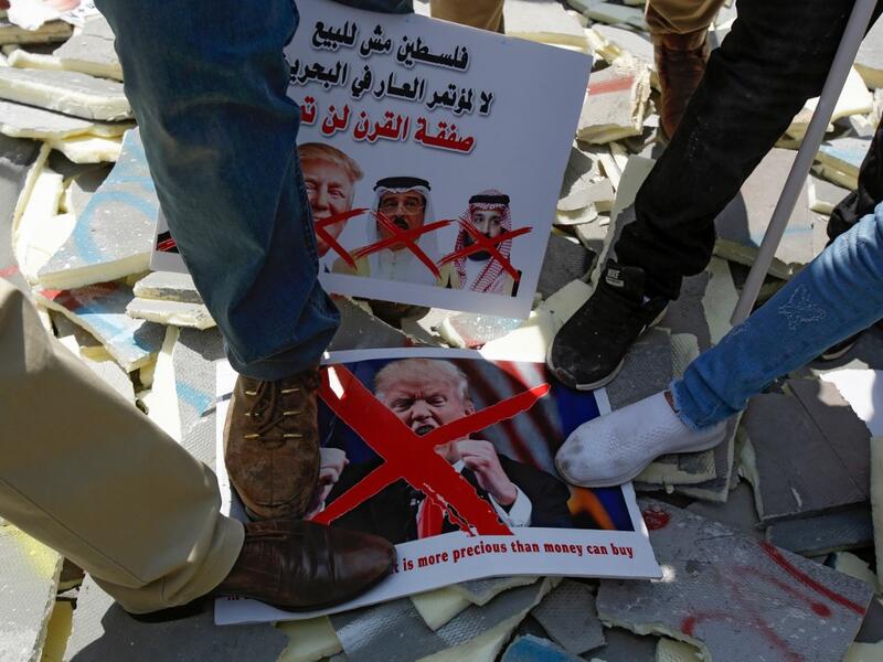 Palestinians stamp on protest signs showing the crossed-out faces of (L to R)  Israeli Prime Minister Benjamin Netanyahu, US President Donald Trump,  King Hamad al-Khalifa of Bahrain, and Saudi Crown Prince Mohammed bin  Salman, with a caption above in Arabic reading "Palestine is not for sale,  no to the conference of shame in Bahrain, the deal of the century will not pass". Musa Al SHAER / AFP