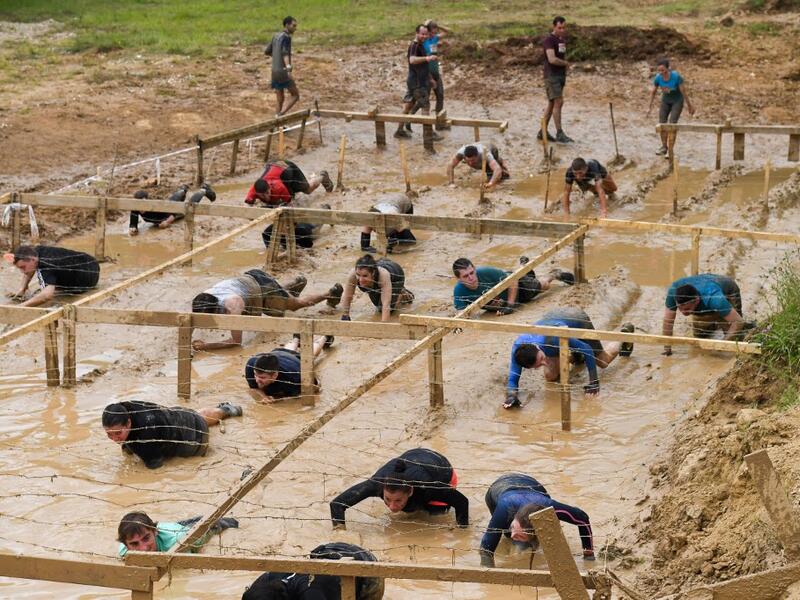 Runners crawl in the mud under barbed wire as they take part in the Mud Day, a 13km race with obstacles in Beynes, near Paris on June 16, 2019.  ALAIN JOCARD / AFP
