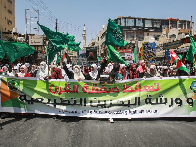 Women march with flags of the Muslim Brotherhood behind a large banner  reading in Arabic "down with the deal of the century and the normalisation  workshop of Bahrain", during a post-Friday prayers demonstration in the  Jordanian capital Amman on June 21, 2019, against US President Donald Trump's "Deal of the Century".  Khalil MAZRAAWI / AFP