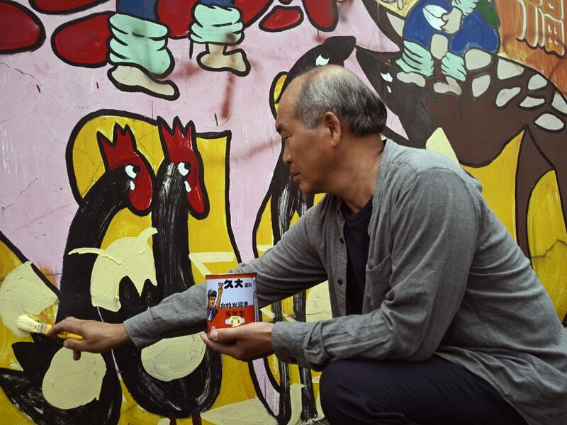 This picture taken on May 21, 2019 shows Hakka graffiti artist Wu Tsun-hsien painting a wall in the Taiwanese village of Ruan Chiao. Nestled in the mist-covered foothills of Taiwan's central mountain range, Ruan Chiao village is virtually devoid of young people, but artist Wu Tsun-hsien is coaxing the Instagram generation back by transforming local homes into a canvas of colour. Sam YEH / AFP