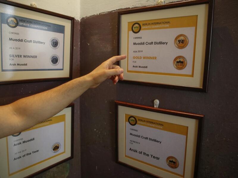 Palestinian distiller Nader Muaddi points at the awards he won in the West Bank village of Beit Jala, near Bethlehem, on June 16, 2019. In his basement, distiller Muaddi made fewer than 500 bottles of liquor last year, but it is earning global acclaim and reviving interest in the Palestinian alcohol sector. On the outskirts of the city famed for Jesus's birth, the 35-year-old illustrates the handcrafted way he makes Arak, an anise-flavoured drink popular in the Middle East and similar to Greek Ouzo, French 