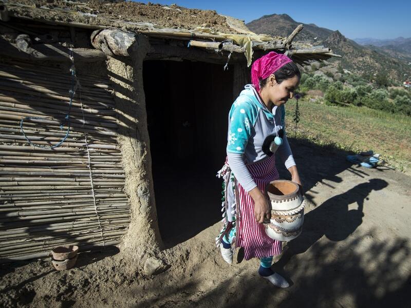Moroccan potter Houda Oumal from the M'tioua tribe carries one of her pottery works near the village of Ourtzagh in the region of Taounate on june 11, 2019. FADEL SENNA / AFP