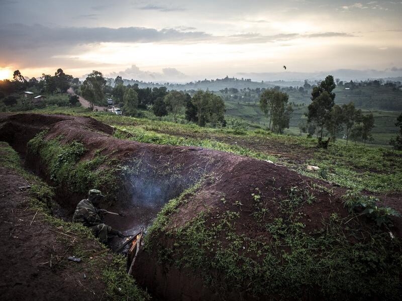 A soldier of the Armed Forces of the Democratic Republic of the Congo (FARDC) warms himself by the fire inside a base on July 4, 2019 in Djugu, eastern DR Congo. John WESSELS / AFP