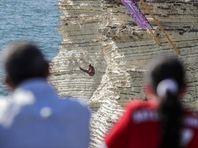 A cliff diver jumps from a platform on the landmark Raouche sea rock off the coast of the Lebanese capital Beirut on July 14, 2019, during the women's 2019 Red Bull Cliff Diving World Series.  ANWAR AMRO / AA / AFP