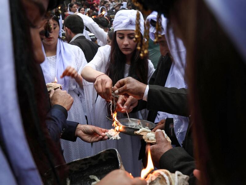 Iraqi Yazidi women light candles outside the Temple of Lalish, in a valley near the Kurdish city of Dohuk about 430 kilometres northwest of the capital Baghdad, on April 16, 2019, during a ceremony marking the Yazidi New Year. Of the 550,000 Yazidis in Iraq before the Islamic State (IS) group invaded their region in 2014, around 100,000 have emigrated abroad and 360,000 remain internally displaced. Roughly 3,300 Yazidis have returned from IS captivity in the last five years, only 10 percent of them men. SAF