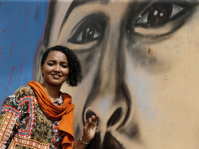 Sudanese activist Eythar Gubara, is pictured in front of a mural painting of Mohamed Mattar, on the wall of a youth club in Bahri in the capital Khartoum's northern district on July 21, 2019.  ASHRAF SHAZLY / AFP