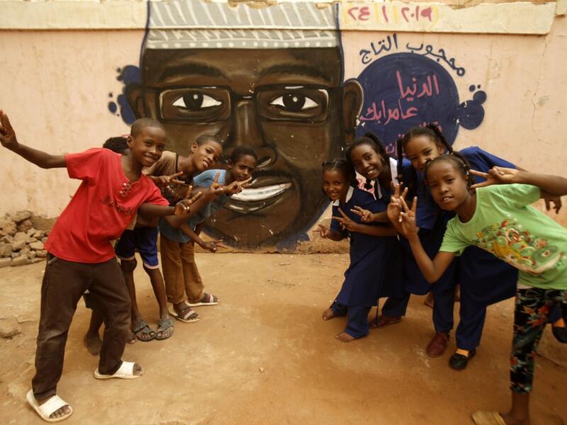 Pupils gesture in front of a mural painting of a protester killed during anti-government protests in the Sudanese capital Khartoum on July 22, 2019.  ASHRAF SHAZLY / AFP