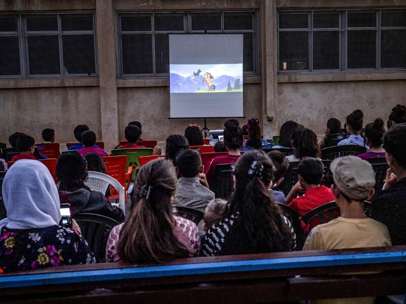 Children attend a film screening as part of the mobile cinema "Komina Film" initiative organised by Syrian-Kurdish filmmaker Shero Hinde, at a school yard in the village of Shaghir Bazar, 55 kilometres southest of Qamishli in the Kurdish-populated areas of northeastern Syria's Hasakeh province, on July 28, 2019.  DELIL SOULEIMAN / AFP