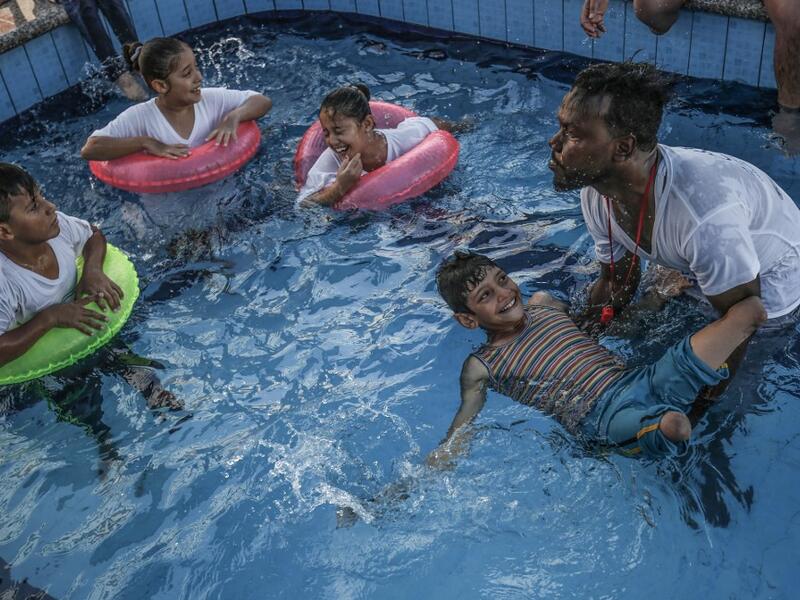  A trainer helps a Palestinian amputee child swim during a summer camp origanized by the Palestinian Children's Relief Fund (PCRF) in the town of Khan Yunis in the southern Gaza strip on August 3, 2019.  SAID KHATIB / AFP