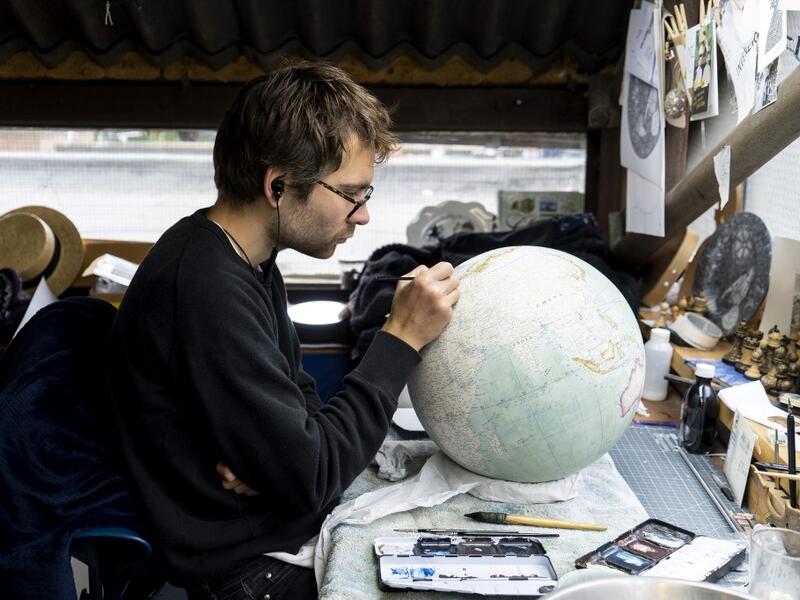 An artist applies paintwork to a globe at the Bellerby and Co Globemakers' workshop and headquarters in Stoke Newington in north London, on July 19, 2019. Niklas HALLE'N / AFP