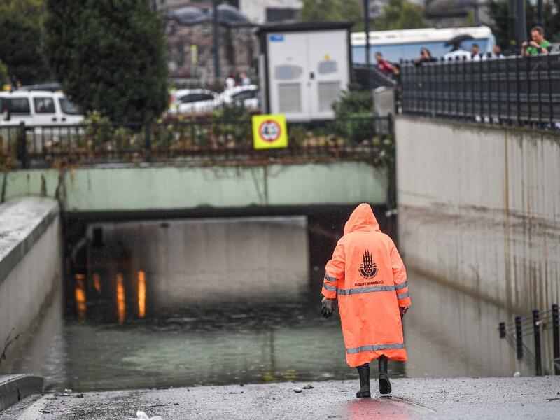 A municipality worker walks near a flooded underpass after a heavy rainfall, in Eminonu district, Istanbul, on August 17, 2019. Turkey's mega city Istanbul was lashed by a heavy rainstorm on August 17, killing a homeless man and leaving parts of the historic Grand Bazaar flooded.  Ozan KOSE / AFP