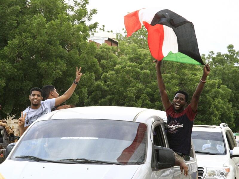 A Sudanese man waves a national flag as people celebrate outside the Friendship Hall in the capital Khartoum where generals and protest leaders signed a historic transitional constitution meant to pave the way for civilian rule in Sudan, on August 17, 2019. (AFP/ File Photo)