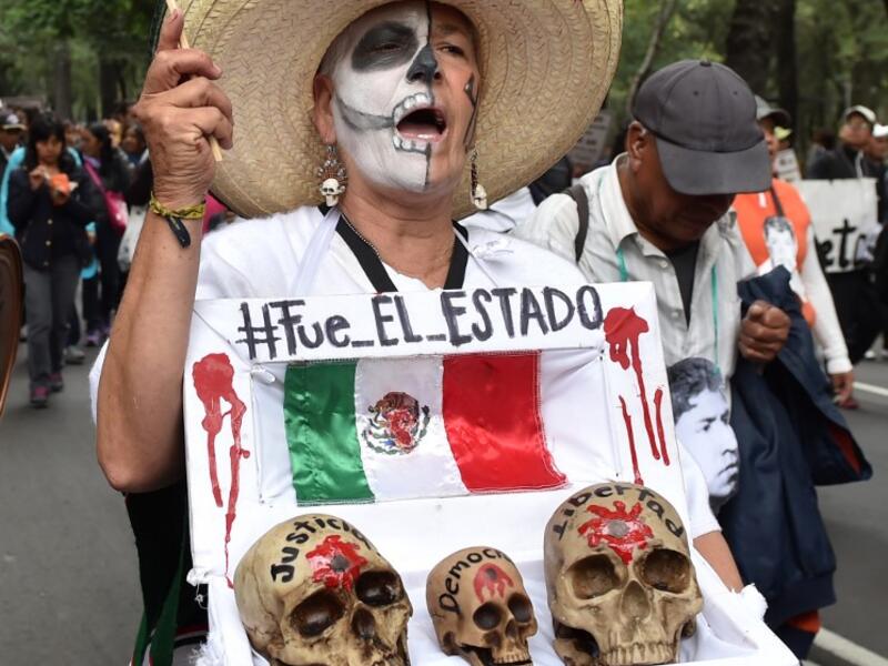 In this file photo taken on September 26, 2015 Mexican activist Julia Klug holds a fake coffin with skulls captioned "Justice, Democracy and Freedom" and a sign reading "It was the State" during a protest in Mexico City, commemorating the first anniversary of the disappearance of the Ayotzinapa students. Yuri CORTEZ / AFP