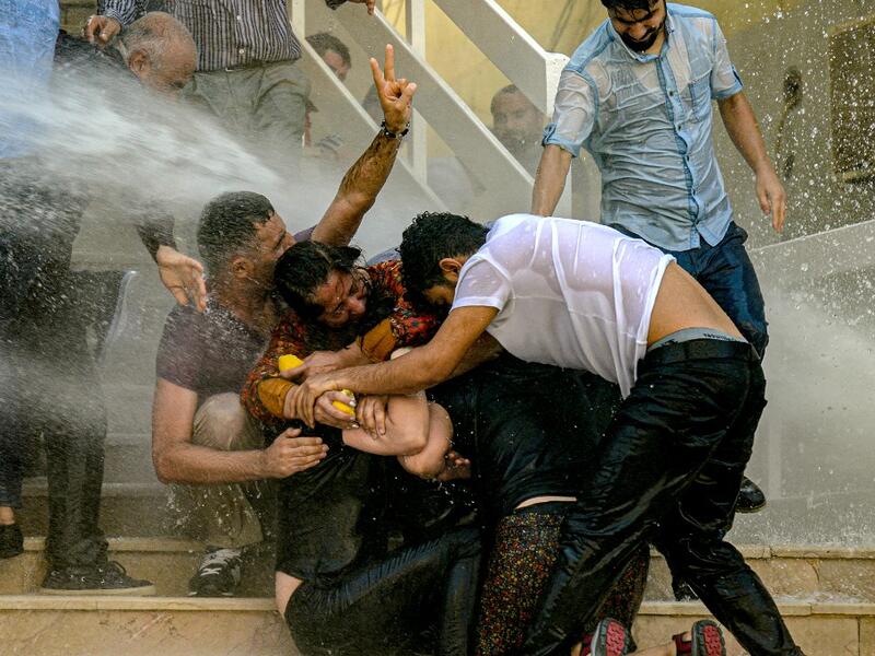 Demonstrators protect each other as they are hit by water cannon during a protest against the replacement of Kurdish mayors with state officials in three cities, in Diyarbakir, in eastern Turkey (AFP)