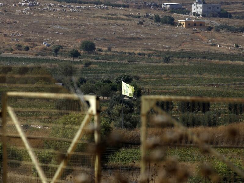 Northern Israeli town of Avivim shows a Hezbollah flag in the Lebanon village of Aitaroun (AFP)