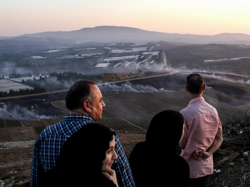 People watch as fires blaze along the Lebanese side of the border with Israel in the Lebanese village of Maroun al-Ras (AFP)