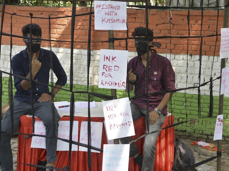 Kashmiri students shows their fingers with red mark as they sit inside a prop cage during a sit-in demonstration against the Indian government's move to revoke the special autonomy of the region guaranteed under Article 370 and 35A, in New Delhi on September 10, 2019. (Sajjad HUSSAIN / AFP)