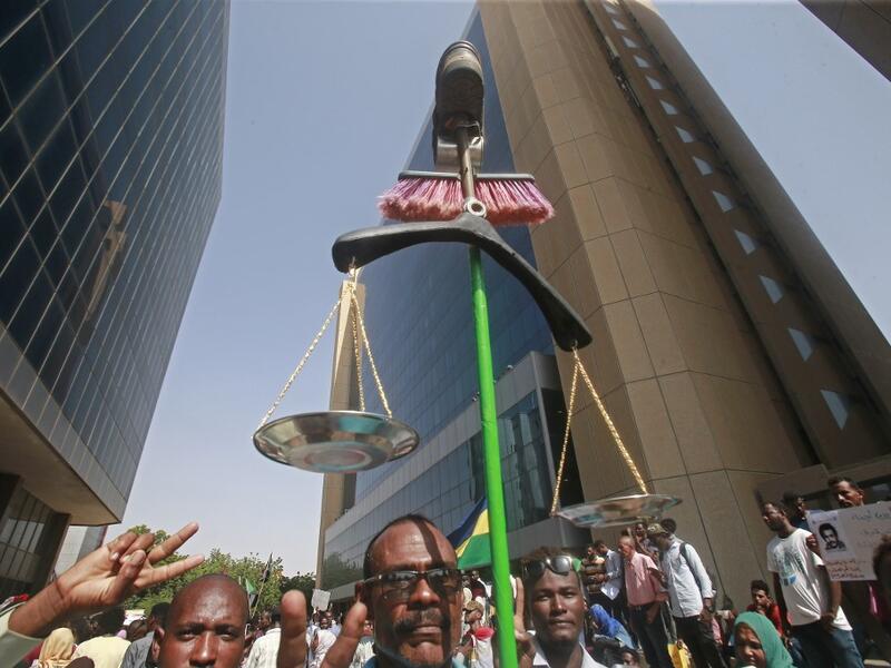 A Sudanese protester carries makeshift scales during a protest asking for the extradition of ousted former president Omar al-Bashir to the International Criminal Court in the capital Khartoum on September 19, 2019. (ASHRAF SHAZLY / AFP)