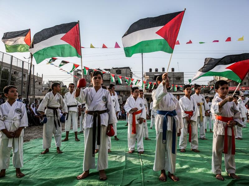 Young Palestinian karatekas wave Palestinian flags during a Karate promotion ceremony at a sporting centre in the Rafah camp for Palestinian refugees in the southern Gaza Strip on September 20, 2019. SAID KHATIB / AFP