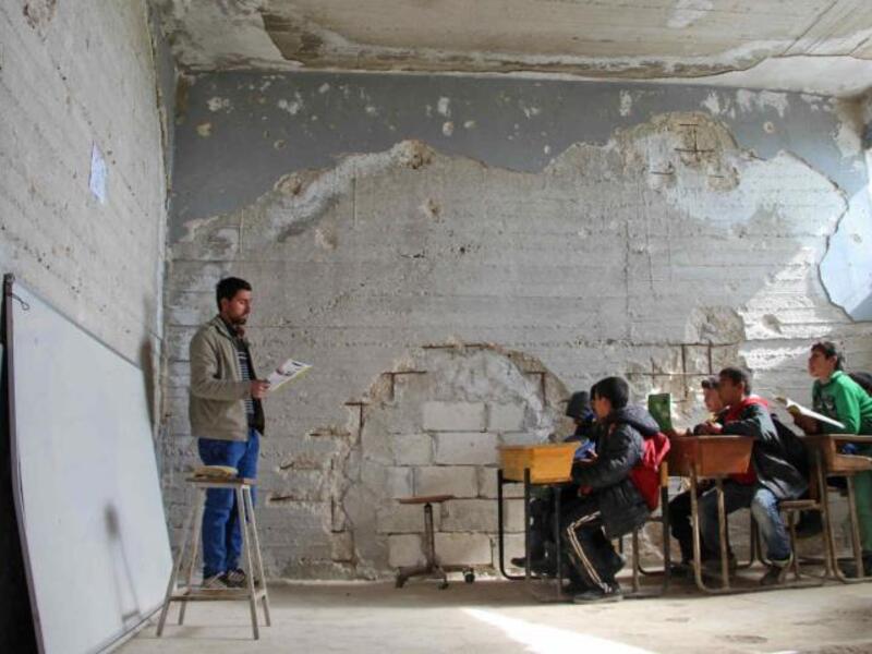 Children attend a class in a school in Idlib that was partially destroyed [AFP/Getty]