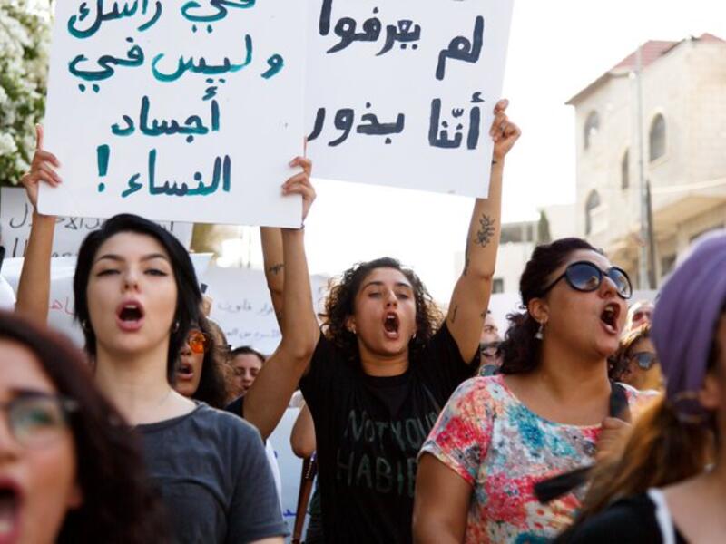 Arabic slogans on placards call for an end to violence against women and introducing a law for family protection against domestic violence."  (Twitter)