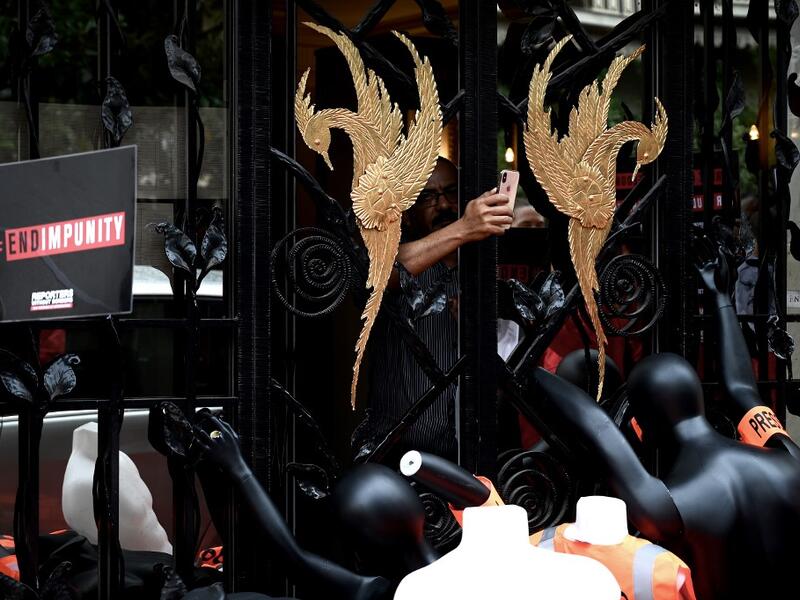 A man takes pictures of dummies with press armbands and jacket piled in front of the Saudi Consulate in Neuilly-Sur-Seine, west of Paris  (AFP)