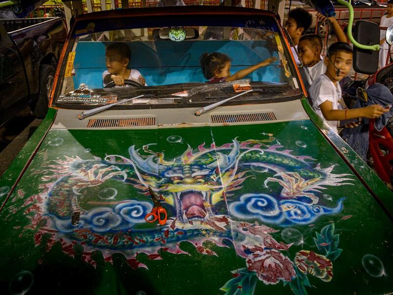 Children play in a car parked next to a Chinese shrine during the annual Vegetarian Festival in Phuket on October 2, 2019. Mladen ANTONOV / AFP