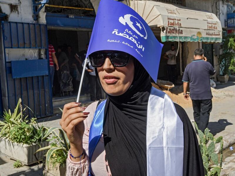 A woman walks holding up a flag of the Islamist-inspired Ennahda party while campaigning in the upcoming upcoming legislative elections in the capital Tunis on October 1, 2019. (FETHI BELAID / AFP)
