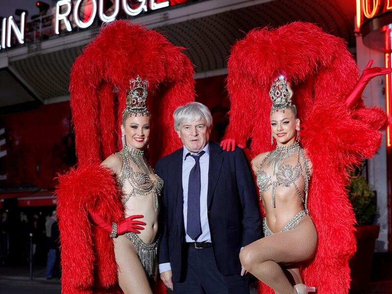 Moulin Rouge cabaret CEO Jean-Jacques Clerico (C) poses with French dancer Mathilde (L) and Australian dancer Rhylee (R) during the celebration of the 130th anniversary of the French oldest cabaret, on October 6, 2019 in Paris.  GEOFFROY VAN DER HASSELT / AFP