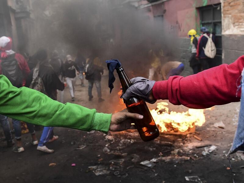 Demonstrators pass on a Molotov cocktail during clashes with riot police in Quito on October 9, 2019 on the second day of violent protests over a fuel price hike ordered by the government to secure an IMF loan. Martin BERNETTI / AFP
