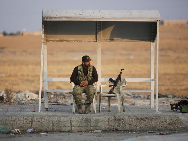 A turkish-backed Syrian fighter sits on the side of the street in the town of Ayn al-Arus, south of the border town of Tal Abyad (AFP)