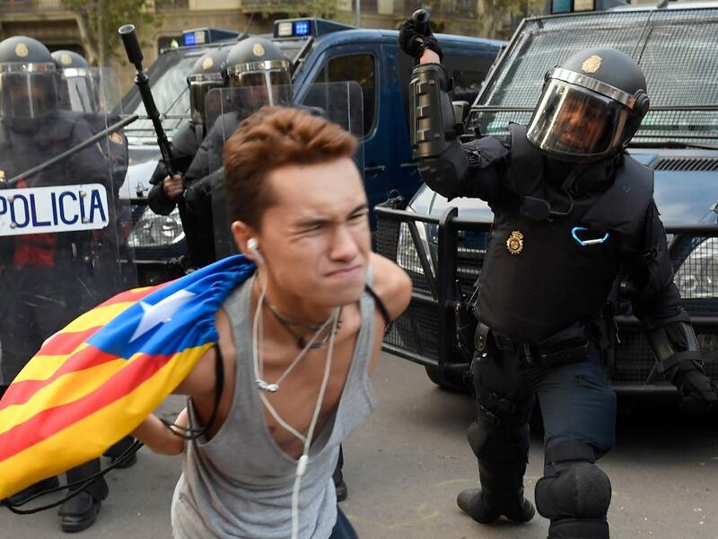 A Spanish national police officer uses his club to hit a protester during a demonstration called the Catalan pro-independence left youth group 'Arran' (AFP)